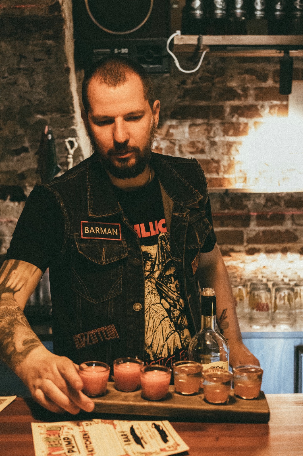 Саша — бармен с шевроном BARMAN и подносом шотов